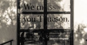 Black and white photo of storefront windows with the text "We Miss you Tucson"